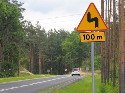 znak ostrzegawczy z tabliczką T-1 niebezpieczne zakręty, pierwszy w lewo