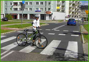 prowadzi rower po przejściu dla pieszych