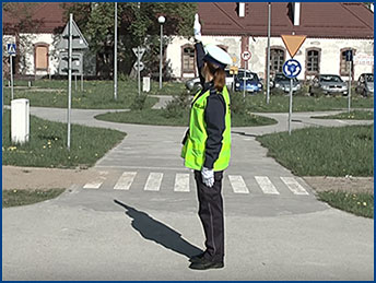 policjant stoi bokiem z podniesioną ręką